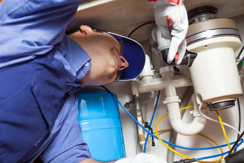 Independent appliance service professional inspecting a garbage disposal under a kitchen sink